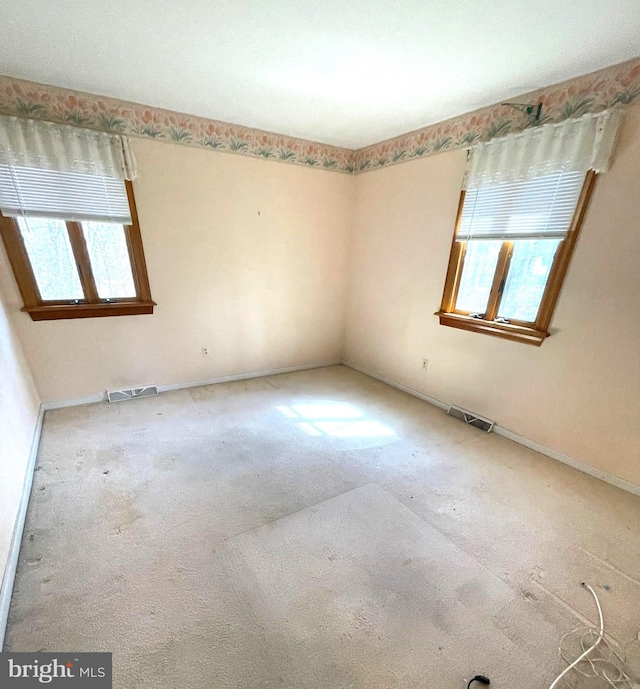 carpeted spare room with a wealth of natural light and visible vents