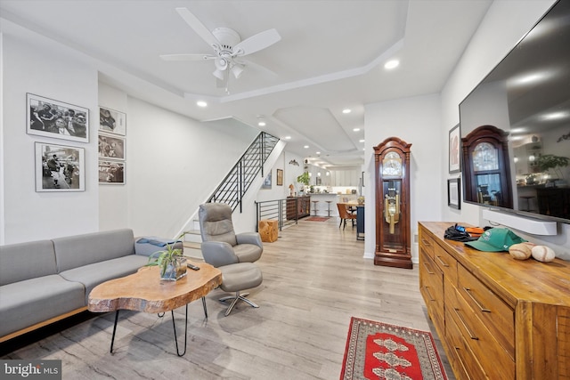 living room with stairs, a ceiling fan, light wood-style flooring, and recessed lighting