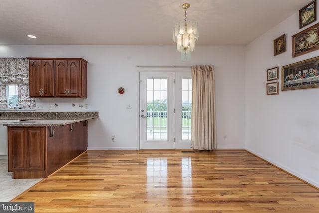 kitchen featuring light wood finished floors, baseboards, pendant lighting, and a notable chandelier