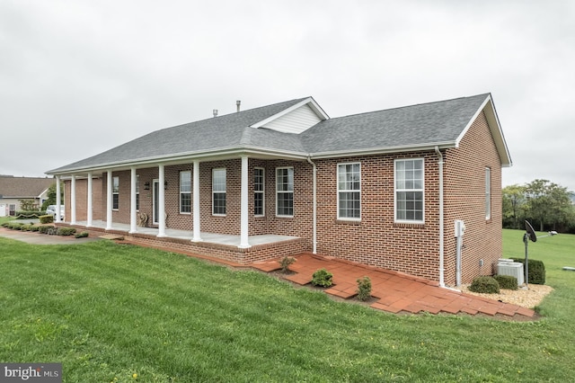 view of front of house featuring a shingled roof, a front lawn, and brick siding