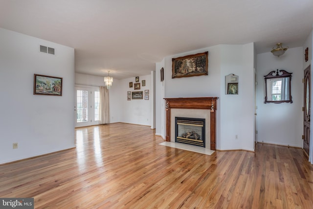 unfurnished living room with light wood finished floors, a fireplace with flush hearth, and a wealth of natural light