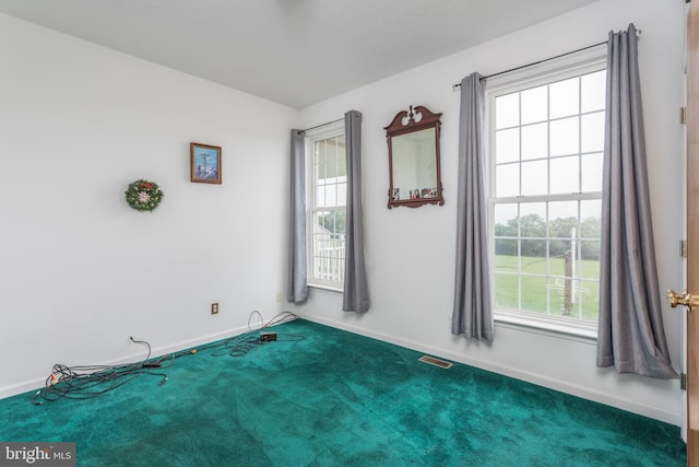 carpeted empty room featuring baseboards, visible vents, and a wealth of natural light