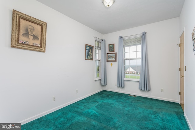 unfurnished room featuring visible vents, baseboards, and dark colored carpet