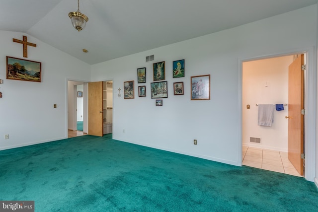 unfurnished bedroom featuring lofted ceiling, ensuite bath, visible vents, and light colored carpet