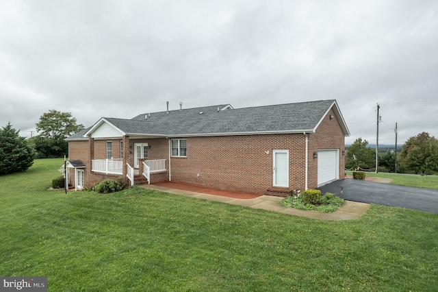 rear view of property with a yard, brick siding, driveway, and an attached garage