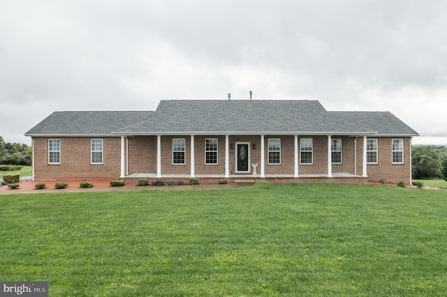 ranch-style house with covered porch, roof with shingles, a front lawn, and brick siding