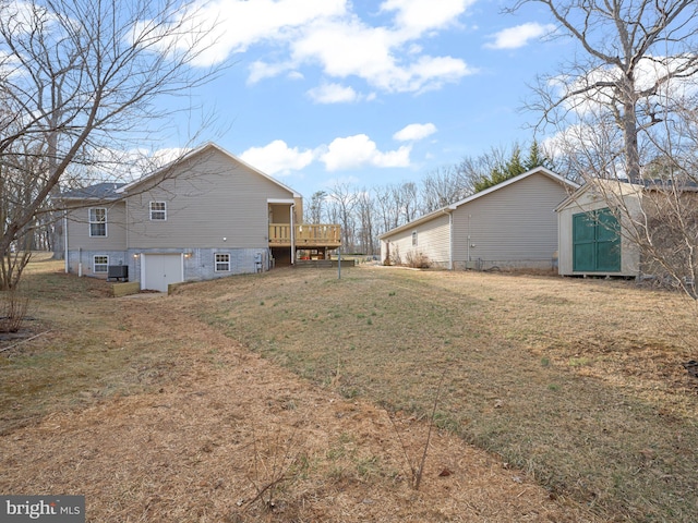 view of home's exterior featuring an outbuilding, a lawn, a wooden deck, and central air condition unit