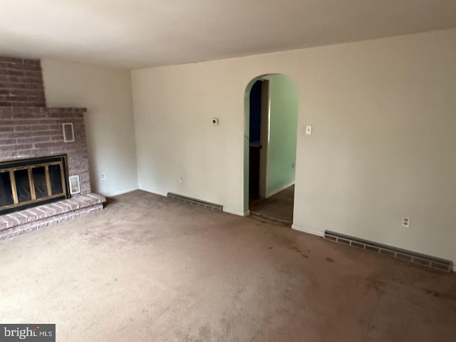 unfurnished living room with arched walkways, a baseboard heating unit, carpet floors, a fireplace, and visible vents