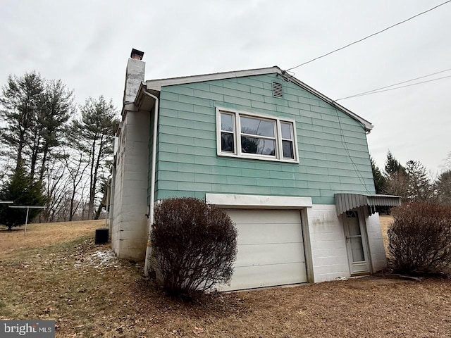 view of side of home featuring a garage and a chimney