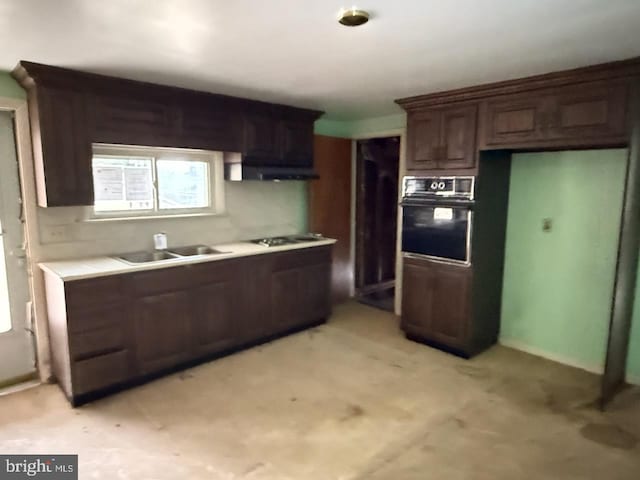 kitchen with under cabinet range hood, a sink, black oven, light countertops, and cooktop