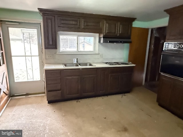 kitchen featuring electric stovetop, a wealth of natural light, light countertops, a sink, and oven