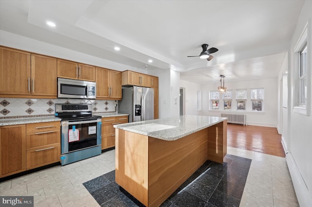 kitchen with a center island, stainless steel appliances, radiator, backsplash, and brown cabinetry