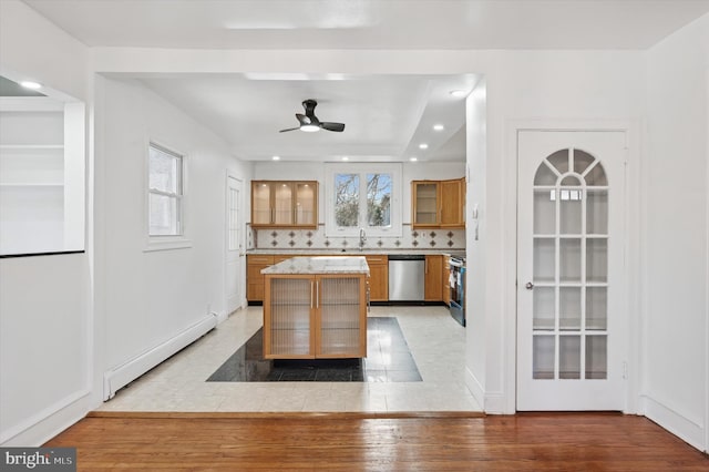 kitchen with appliances with stainless steel finishes, a center island, light wood-type flooring, a baseboard heating unit, and a sink