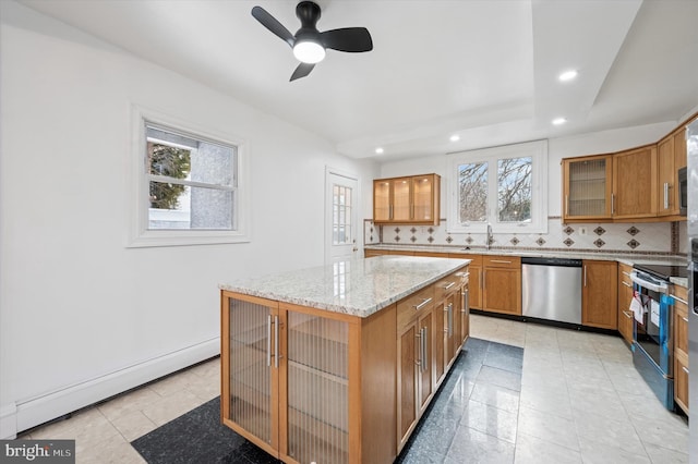 kitchen with a baseboard radiator, stainless steel appliances, a sink, light stone countertops, and tasteful backsplash