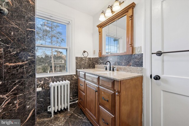 bathroom with vanity, tile walls, marble finish floor, wainscoting, and radiator