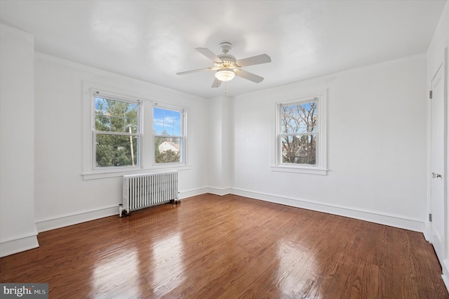 spare room featuring radiator heating unit, baseboards, ceiling fan, and wood finished floors