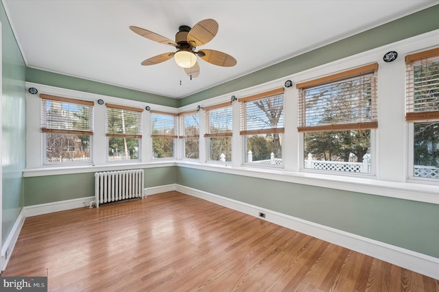 unfurnished sunroom featuring ceiling fan and radiator heating unit