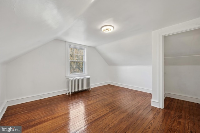 additional living space with radiator, vaulted ceiling, baseboards, and hardwood / wood-style flooring