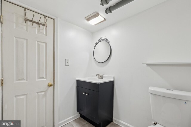 bathroom featuring toilet, tile patterned floors, baseboards, and vanity