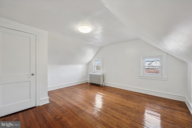 additional living space with lofted ceiling, radiator, baseboards, and hardwood / wood-style flooring