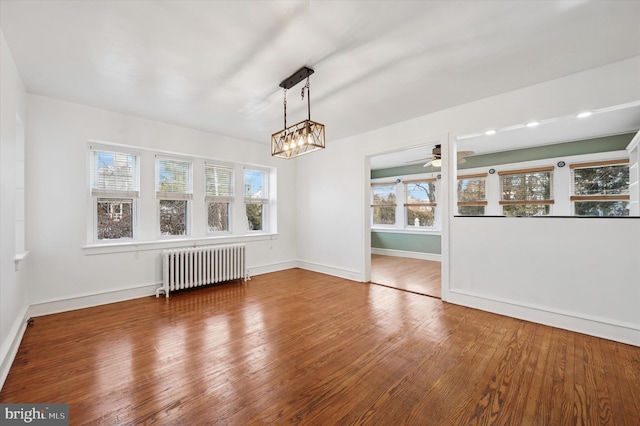 unfurnished dining area with radiator heating unit, wood-type flooring, a wealth of natural light, and baseboards