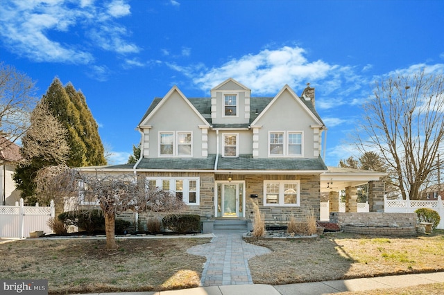 view of front of house with stone siding, a chimney, fence, and stucco siding