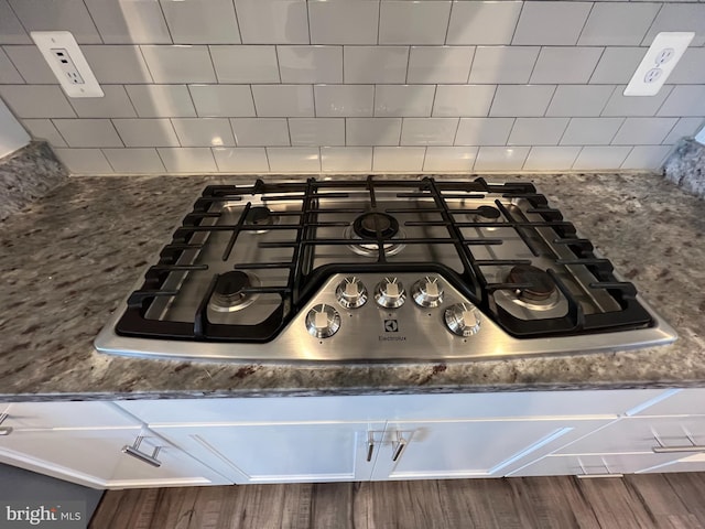 room details with stone countertops, stainless steel gas stovetop, decorative backsplash, and wood finished floors