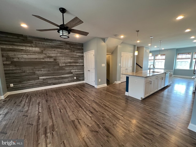 kitchen with a sink, wood walls, an accent wall, and dark wood-style flooring