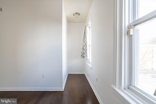 hall with dark wood-style floors and baseboards