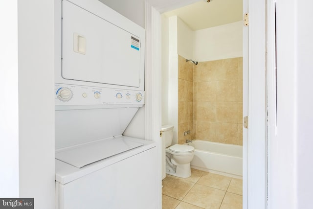 full bathroom featuring stacked washing maching and dryer, shower / tub combination, toilet, and tile patterned floors