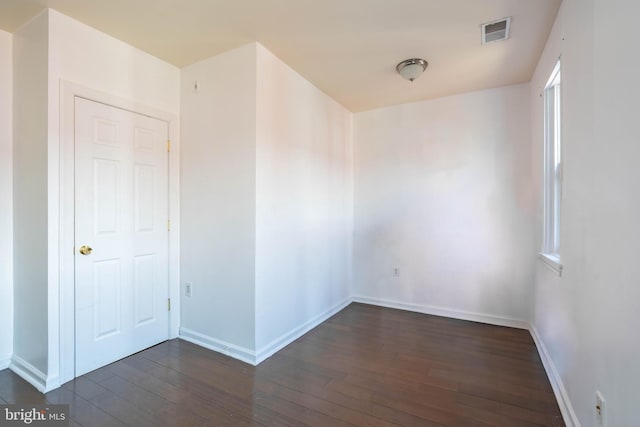 spare room featuring dark wood finished floors, visible vents, and baseboards