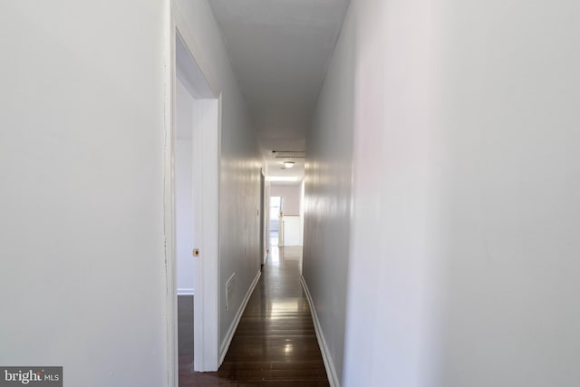 corridor featuring dark wood finished floors and baseboards