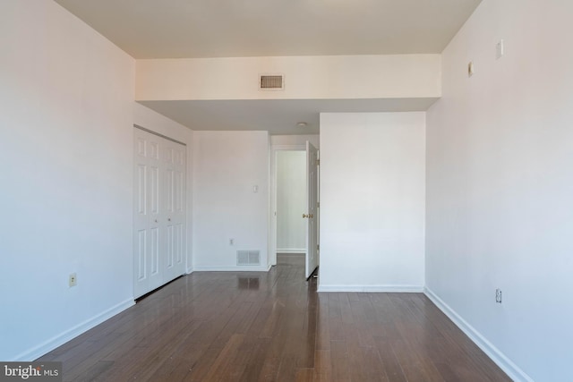 unfurnished bedroom featuring baseboards, a closet, visible vents, and dark wood-style flooring