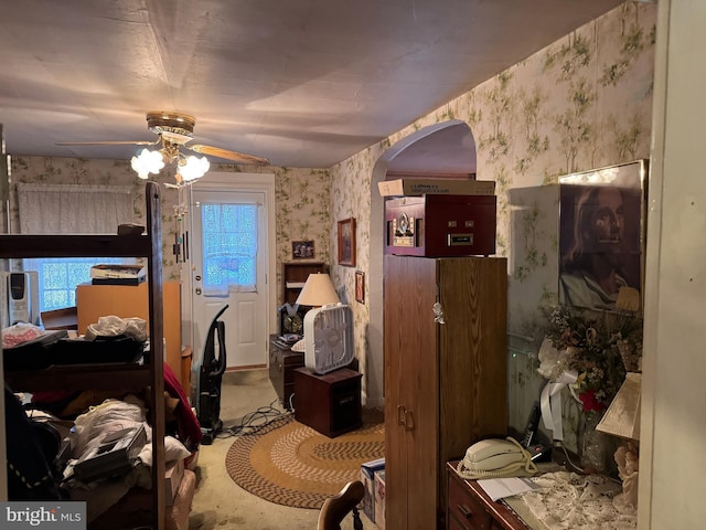 bedroom with arched walkways, ceiling fan, multiple windows, and wallpapered walls