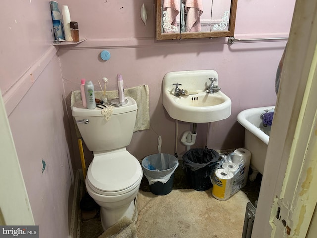 full bathroom with toilet, a soaking tub, and a sink