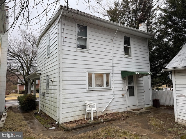 back of house featuring a chimney and fence