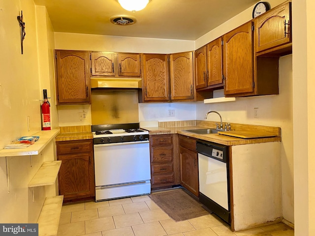 kitchen featuring visible vents, ventilation hood, brown cabinets, white appliances, and a sink