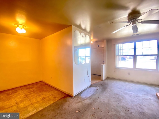 carpeted foyer featuring tile patterned floors, visible vents, and a ceiling fan