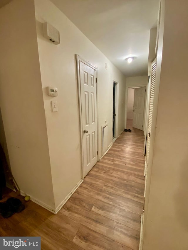 hall with light wood-type flooring and baseboards