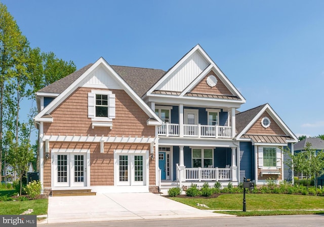 view of front of house featuring roof with shingles, covered porch, a standing seam roof, a balcony, and a front lawn