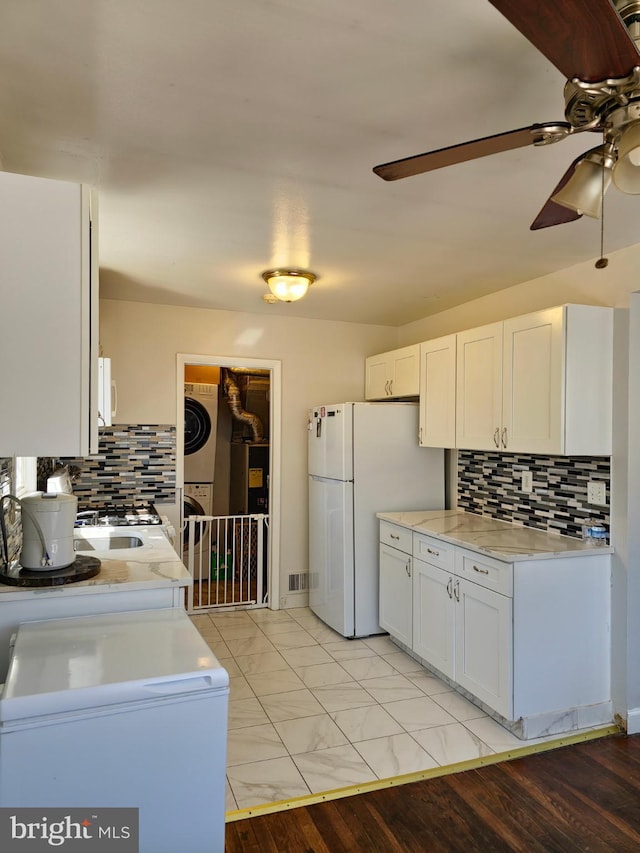 1205 Stratwood Ave, Oxon Hill, MD 20745 - kitchen featuring white appliances, a ceiling fan, decorative backsplash, white cabinetry, and stacked washer / dryer