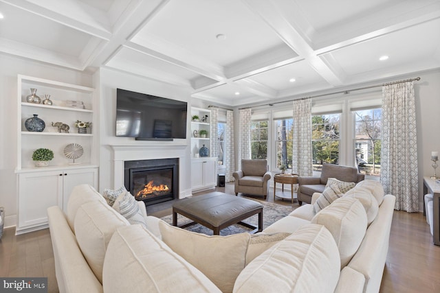 living room featuring wood finished floors, coffered ceiling, a glass covered fireplace, and beam ceiling