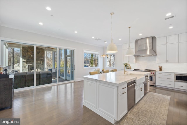 kitchen with stainless steel appliances, tasteful backsplash, wood-type flooring, visible vents, and wall chimney exhaust hood