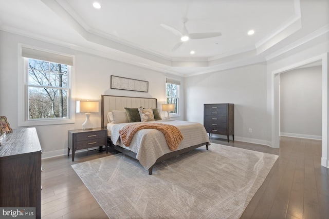 bedroom with baseboards, a tray ceiling, hardwood / wood-style floors, and ornamental molding