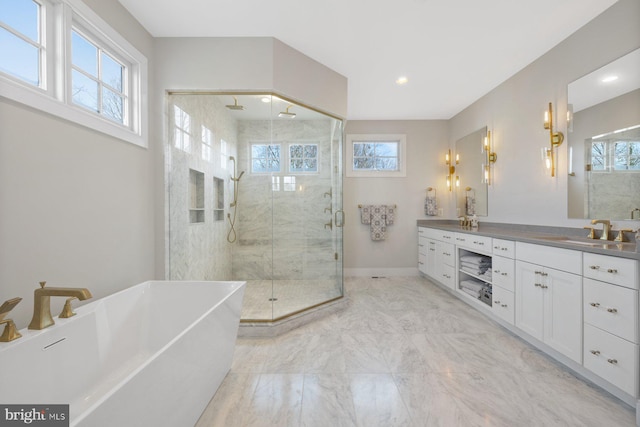 full bath with plenty of natural light, a stall shower, a sink, and double vanity