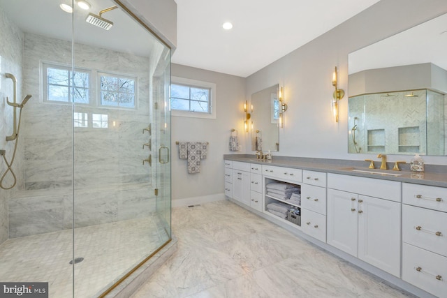 bathroom with marble finish floor, double vanity, a stall shower, a sink, and baseboards