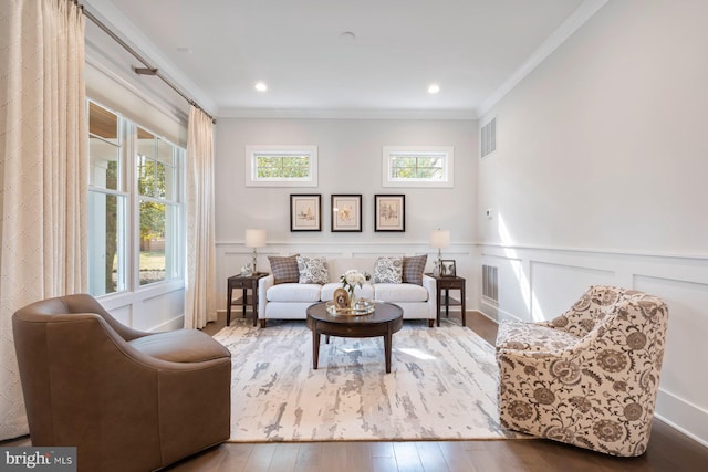 living room featuring a wainscoted wall, ornamental molding, wood finished floors, and visible vents