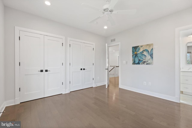 unfurnished bedroom featuring recessed lighting, wood finished floors, visible vents, and multiple closets