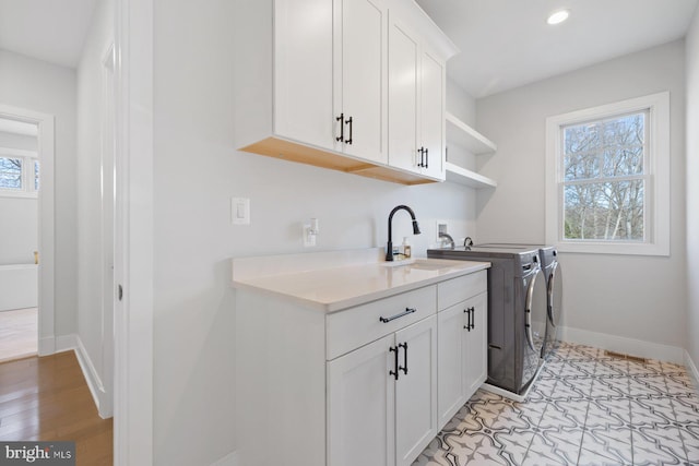 clothes washing area featuring cabinet space, baseboards, washing machine and dryer, a sink, and recessed lighting