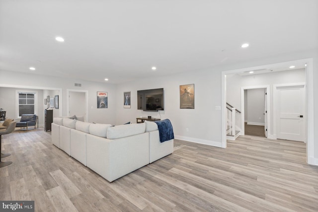 living area featuring recessed lighting, baseboards, light wood finished floors, and stairs